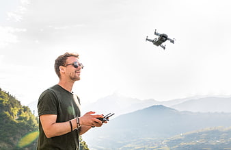 Young man flying a drone in a mountainous landscape