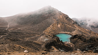 Turquoise crater lake in misty volcanic mountain landscape