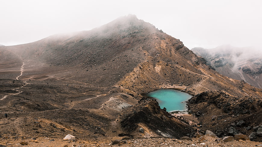 Turquoise crater lake in misty volcanic mountain landscape
