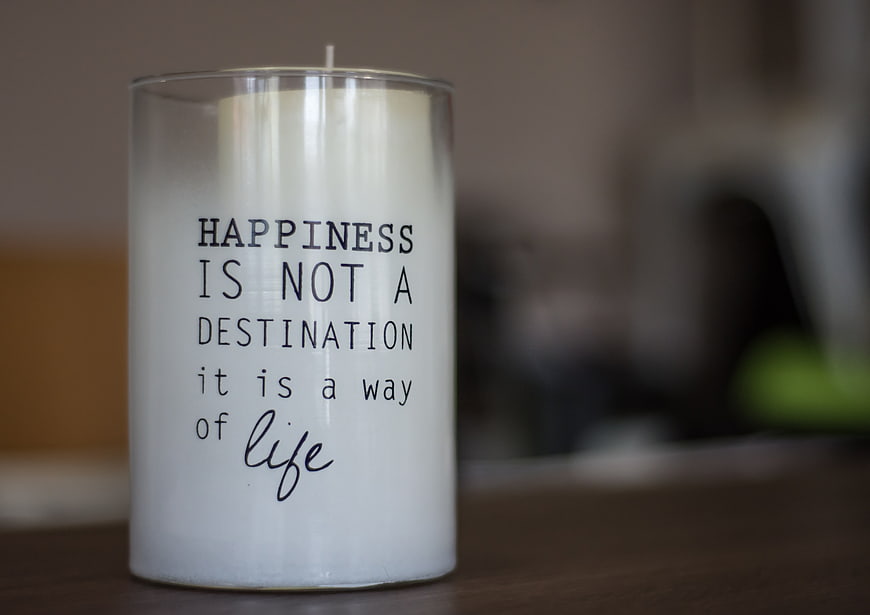 White Candle with Inspirational Quote on Wooden Table