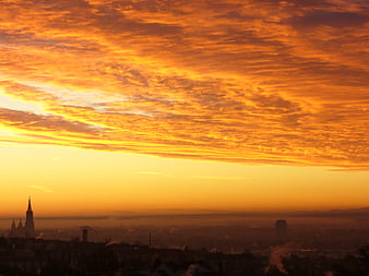 Vibrant Orange Sunrise Over Hazy City Skyline