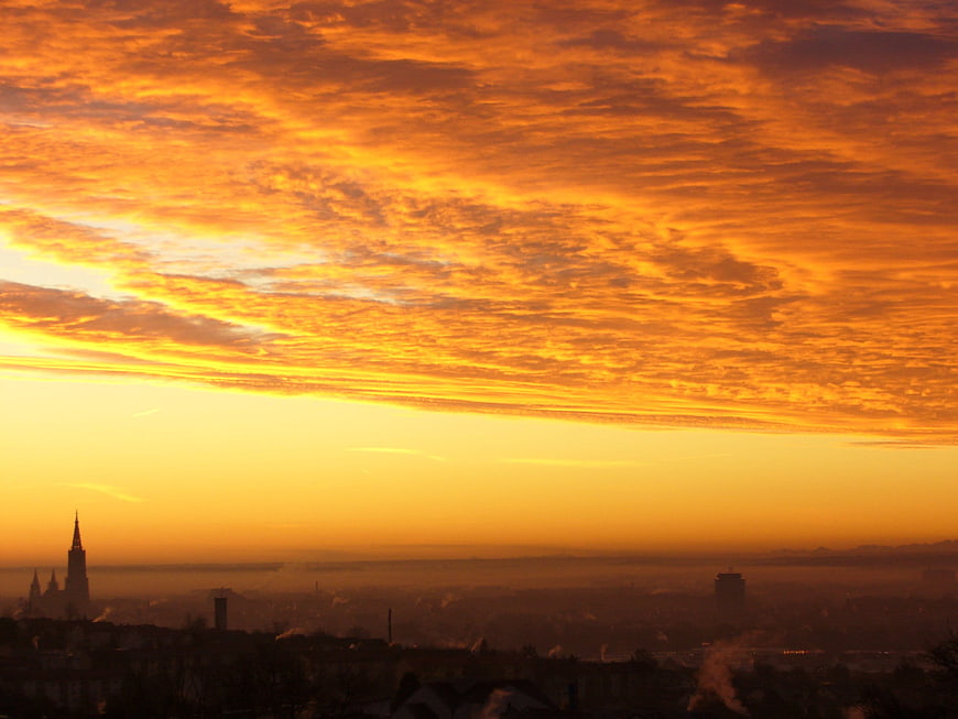 Vibrant Orange Sunrise Over Hazy City Skyline