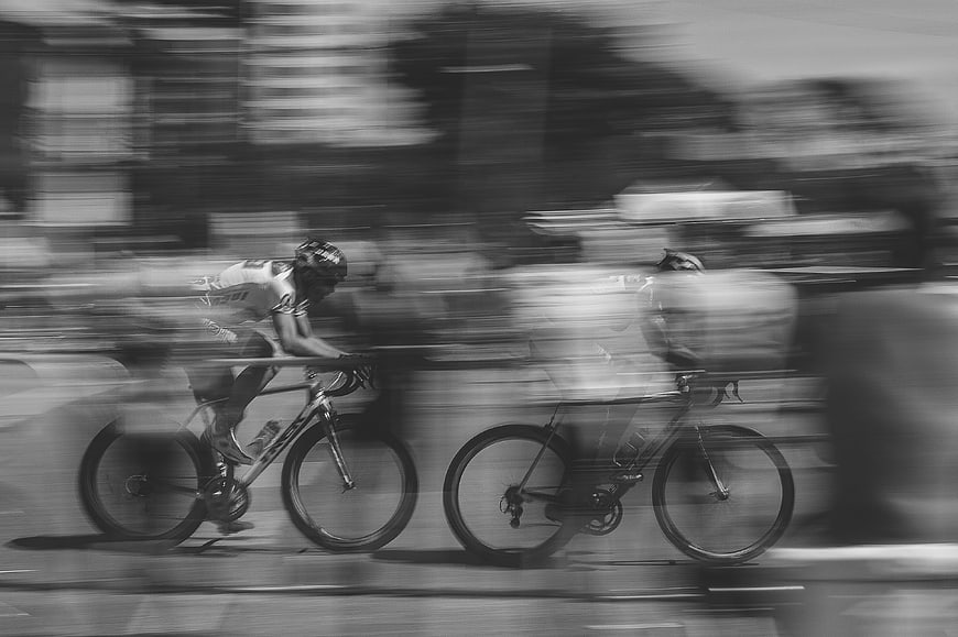 Black and white motion blur of cyclists racing on a road