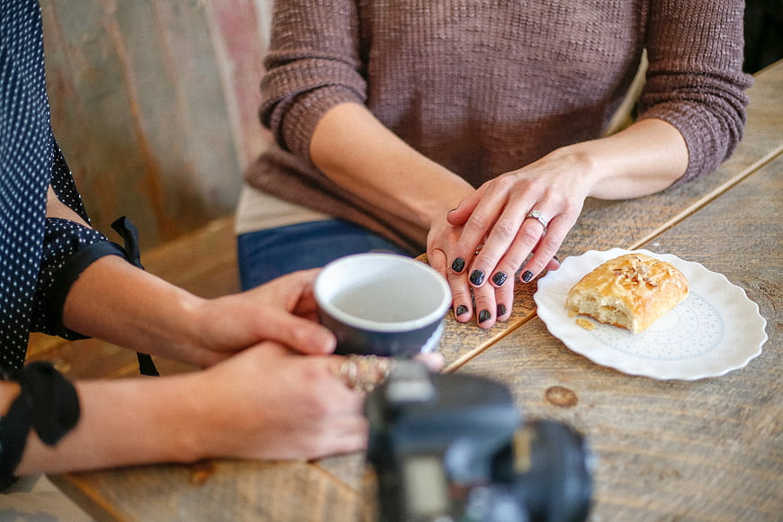 Two women sharing coffee and pastry at rustic wooden table