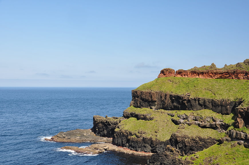 Dramatic coastal cliffs with green grass and blue ocean