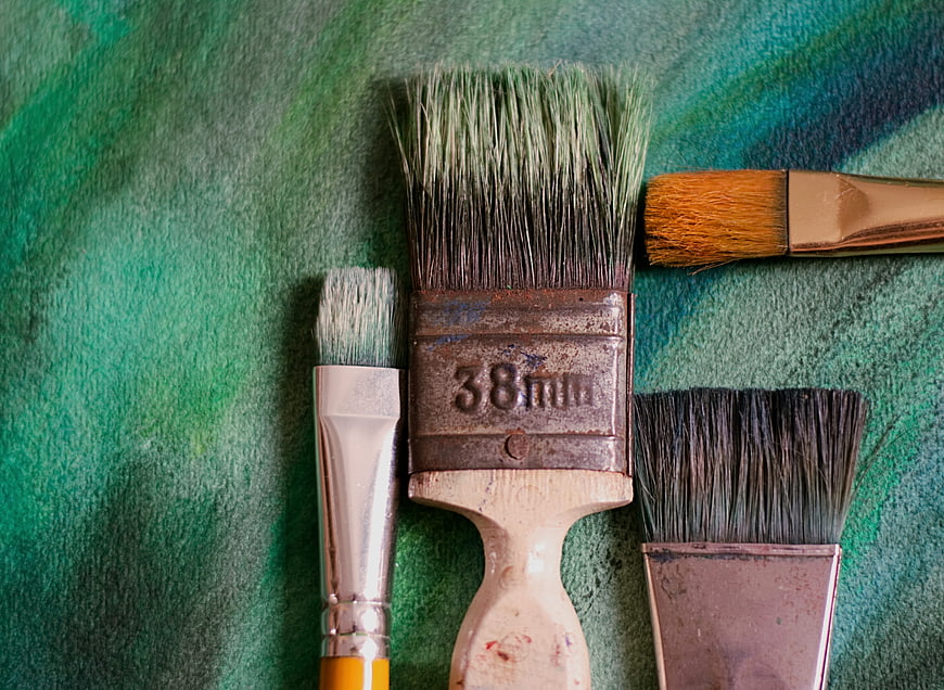 Used Paintbrushes on Green Painted Canvas Background
