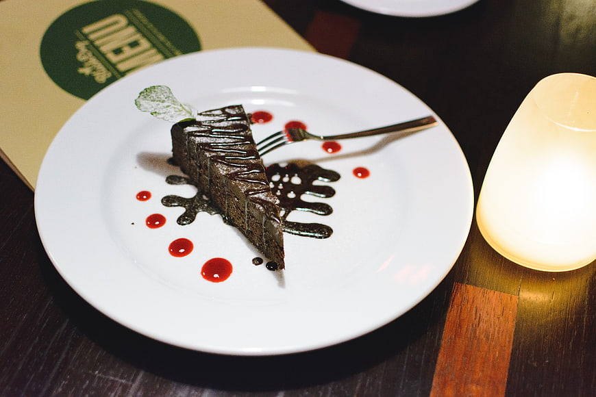 Gourmet chocolate cake slice with berry sauce on white plate