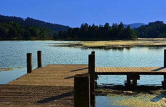 Wooden Dock Extending into Calm Lake with Forest Hills