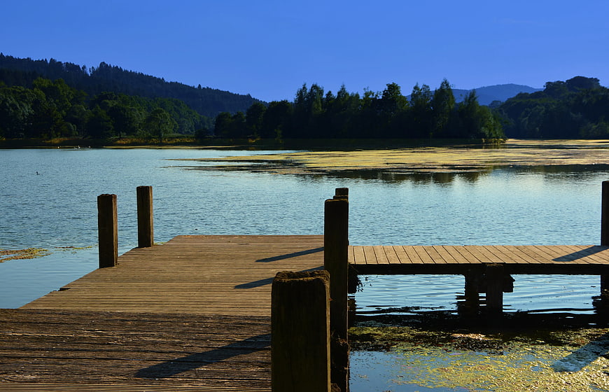 Wooden Dock Extending into Calm Lake with Forest Hills