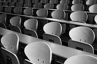 Black and white rows of empty wooden lecture hall seats