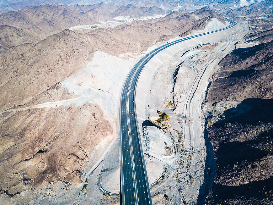 Aerial View of Winding Highway Through Arid Desert Mountains