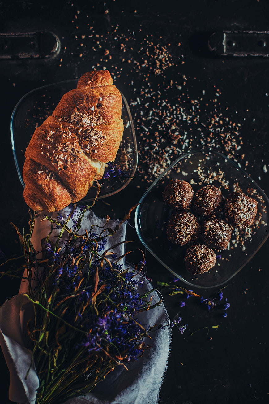 Dark moody flat lay of croissant and chocolate truffles with lavender