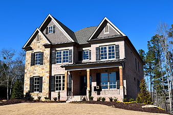 Modern two-story brick and stone house exterior with blue sky