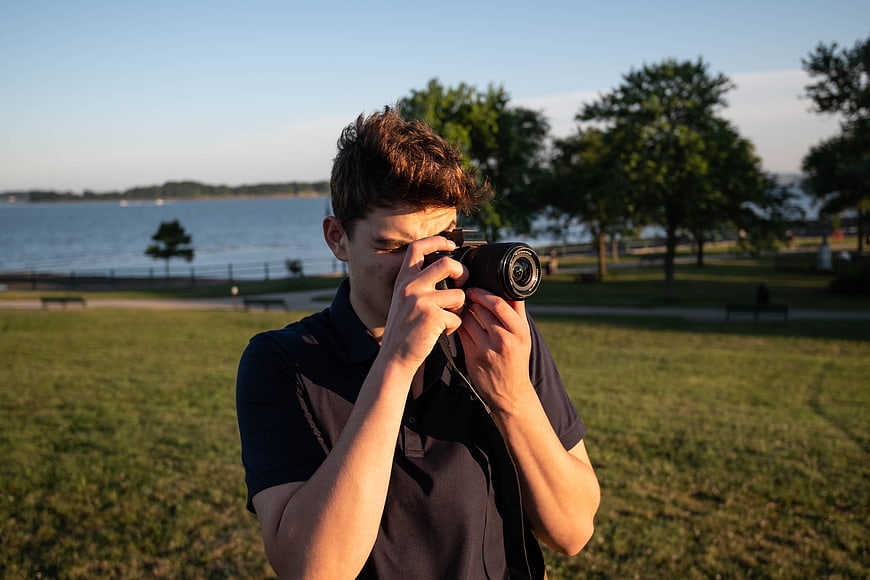 Young Man Taking Photo with Camera in Park