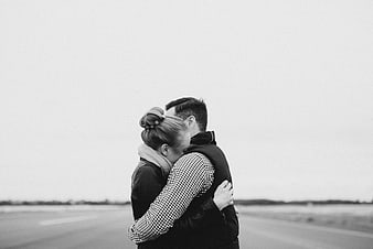 Black and white photo of couple hugging on road
