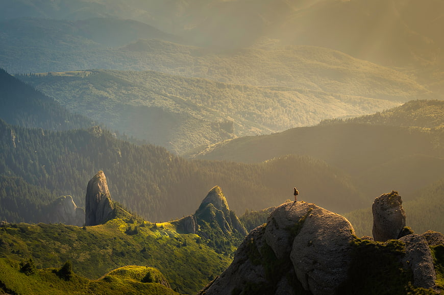 Lone Hiker on Rocky Peak Overlooking Misty Mountain Forest