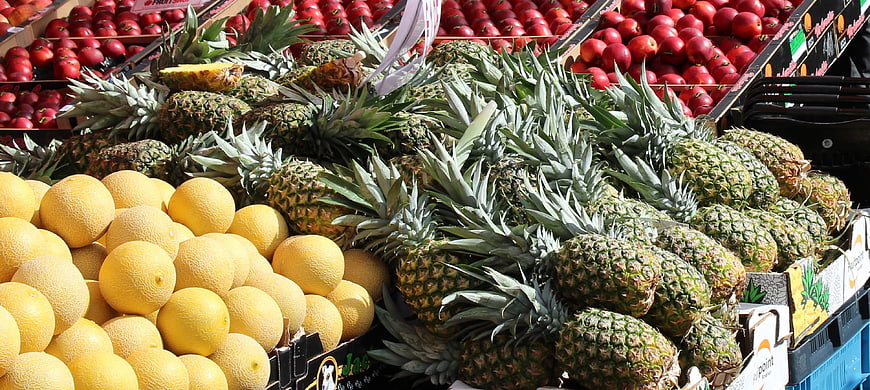 Fresh Pineapples, Melons, and Apples at Outdoor Market