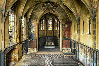 Interior of abandoned gothic chapel with stained glass and frescoes