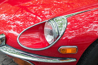 Close-up of red vintage car headlight and chrome bumper