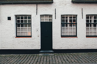 White brick house facade with dark green door and windows