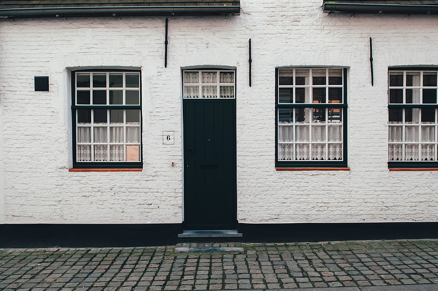 White brick house facade with dark green door and windows