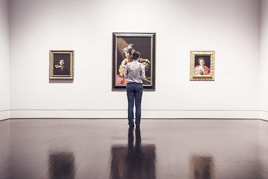 Woman viewing classical paintings in a modern art gallery