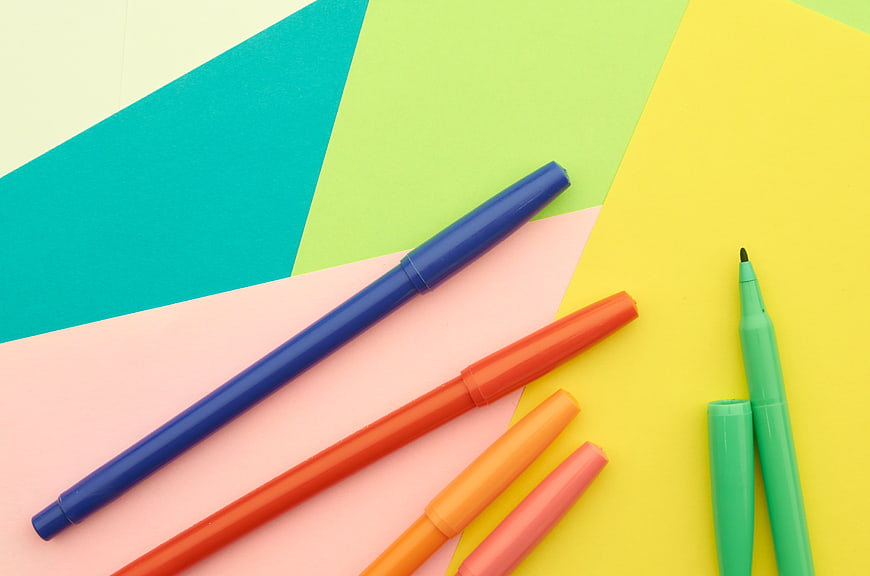 Colorful markers on geometric pastel paper background