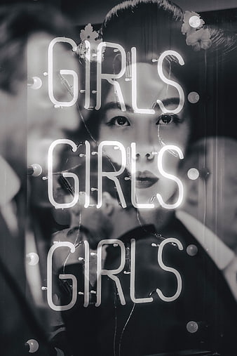 Black and white woman behind neon girls sign