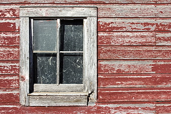 Weathered red barn window with peeling paint and rustic wood texture