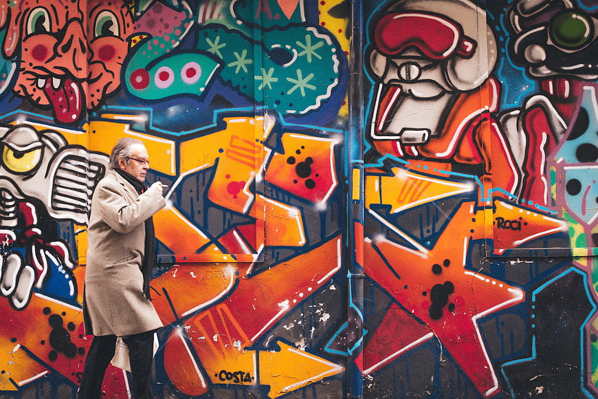 Man Smoking in Front of Colorful Graffiti Wall
