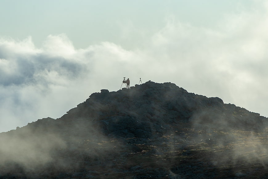 Photographer on Rocky Mountain Peak Above Clouds