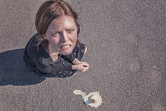 Angry woman looking down at spilled ice cream cone on pavement