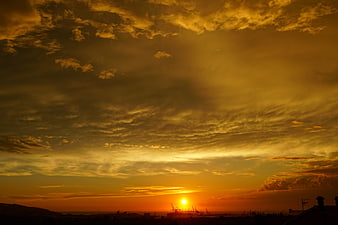 Dramatic golden sunset over industrial port silhouette