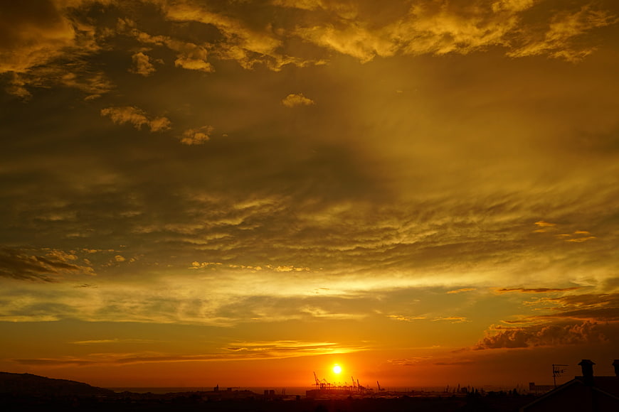 Dramatic golden sunset over industrial port silhouette