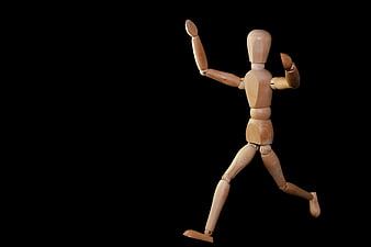 Wooden artist mannequin running pose on black background