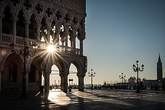 Sunburst through Doge's Palace arches in Venice at dawn