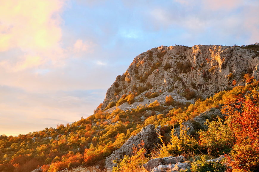 Golden sunset on rocky mountain with autumn foliage