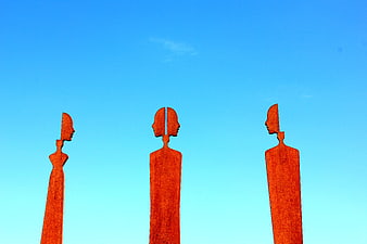 Three Rusty Metal Sculptures Against Blue Sky