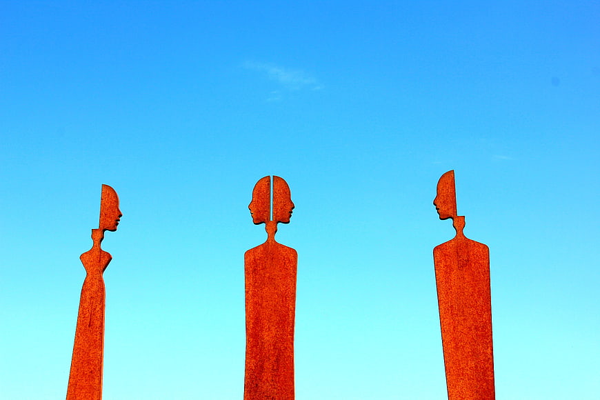 Three Rusty Metal Sculptures Against Blue Sky