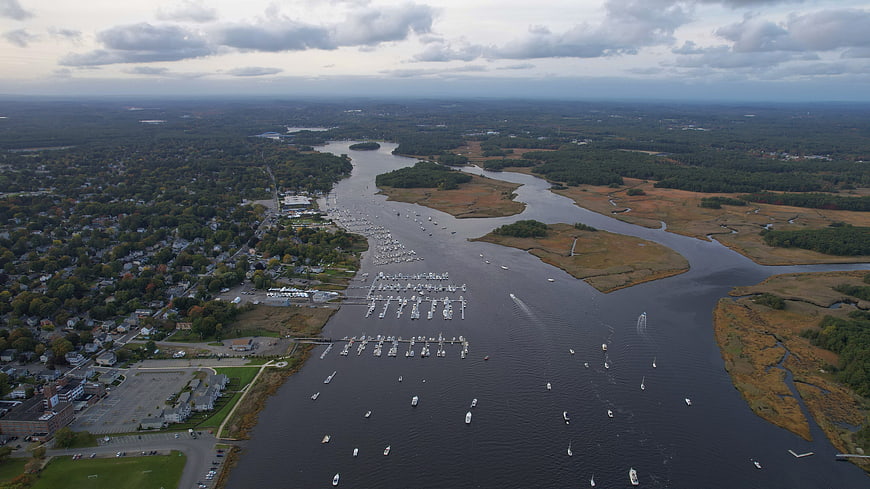 Aerial view of coastal harbor with boats and marshland
