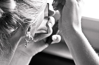 Close-up of woman applying makeup with mirror and earring