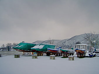 Snow-covered boats resting on a frozen lake in winter