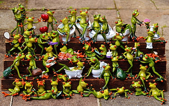 Collection of whimsical green frog figurines on wooden steps