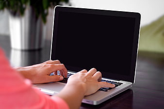 Hands typing on laptop with black screen