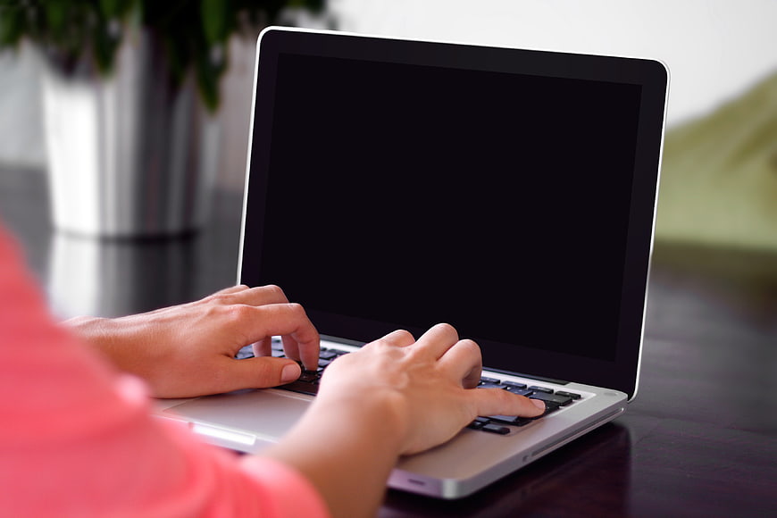 Hands typing on laptop with black screen