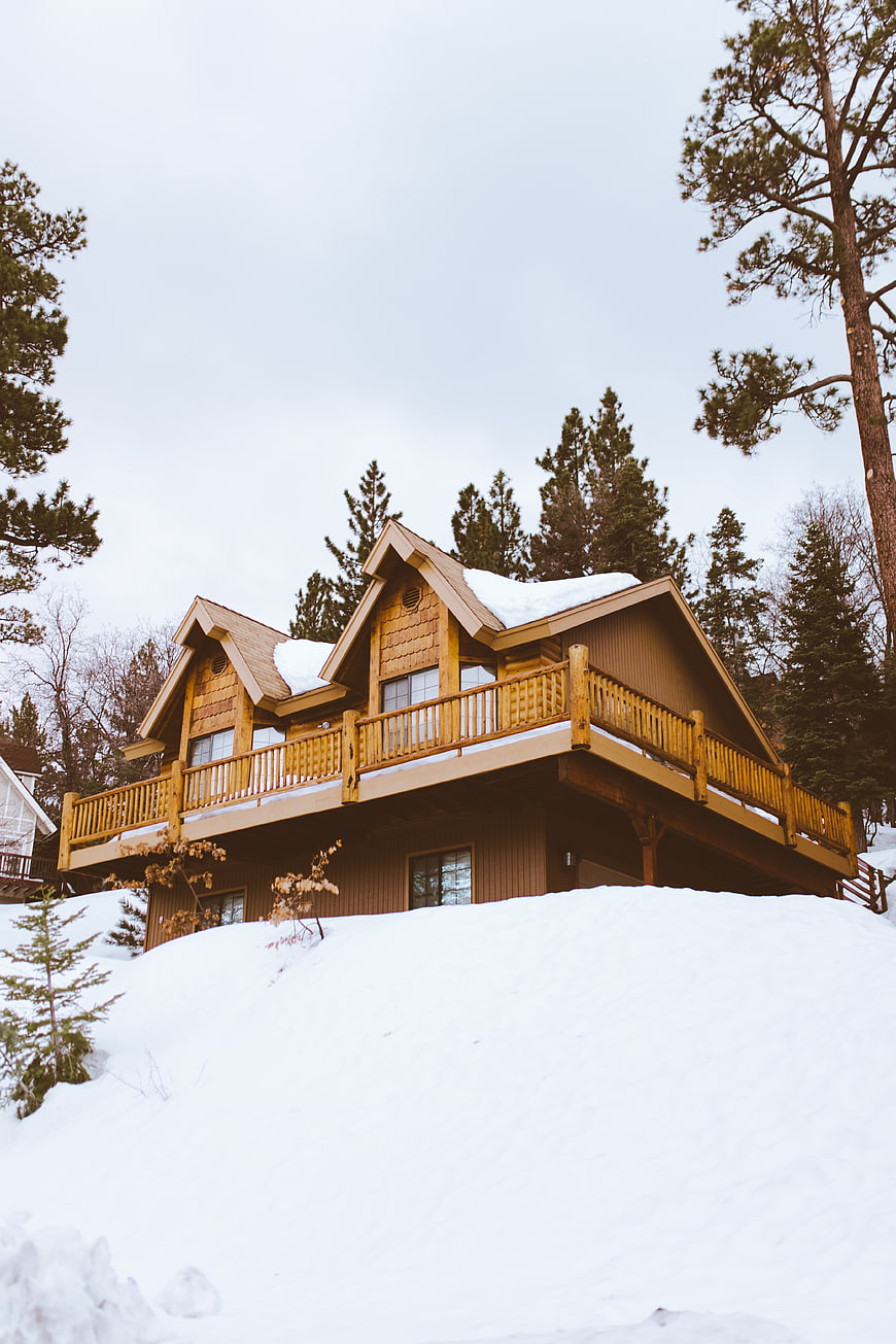 Cozy wooden cabin on snowy hill in winter forest