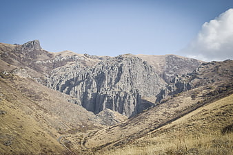Rugged mountain landscape with dry grassy slopes and rocky cliffs