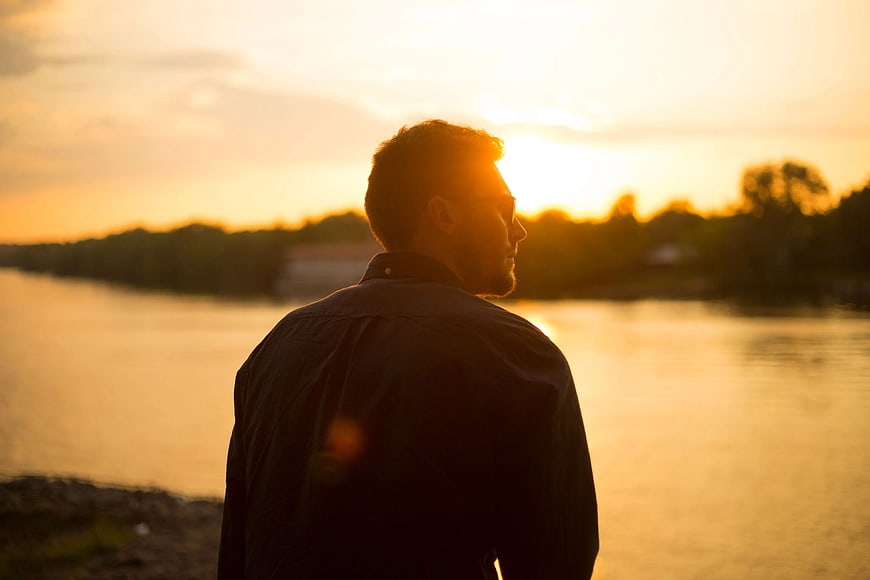 Man Silhouette Looking at Sunset Over River