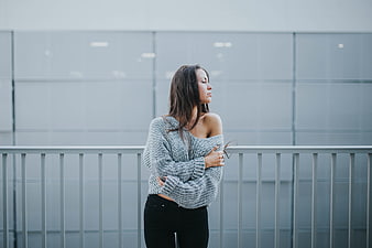 Woman in Oversized Sweater Standing by Modern Glass Wall