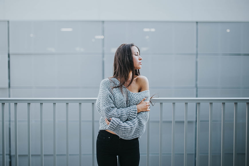 Woman in Oversized Sweater Standing by Modern Glass Wall